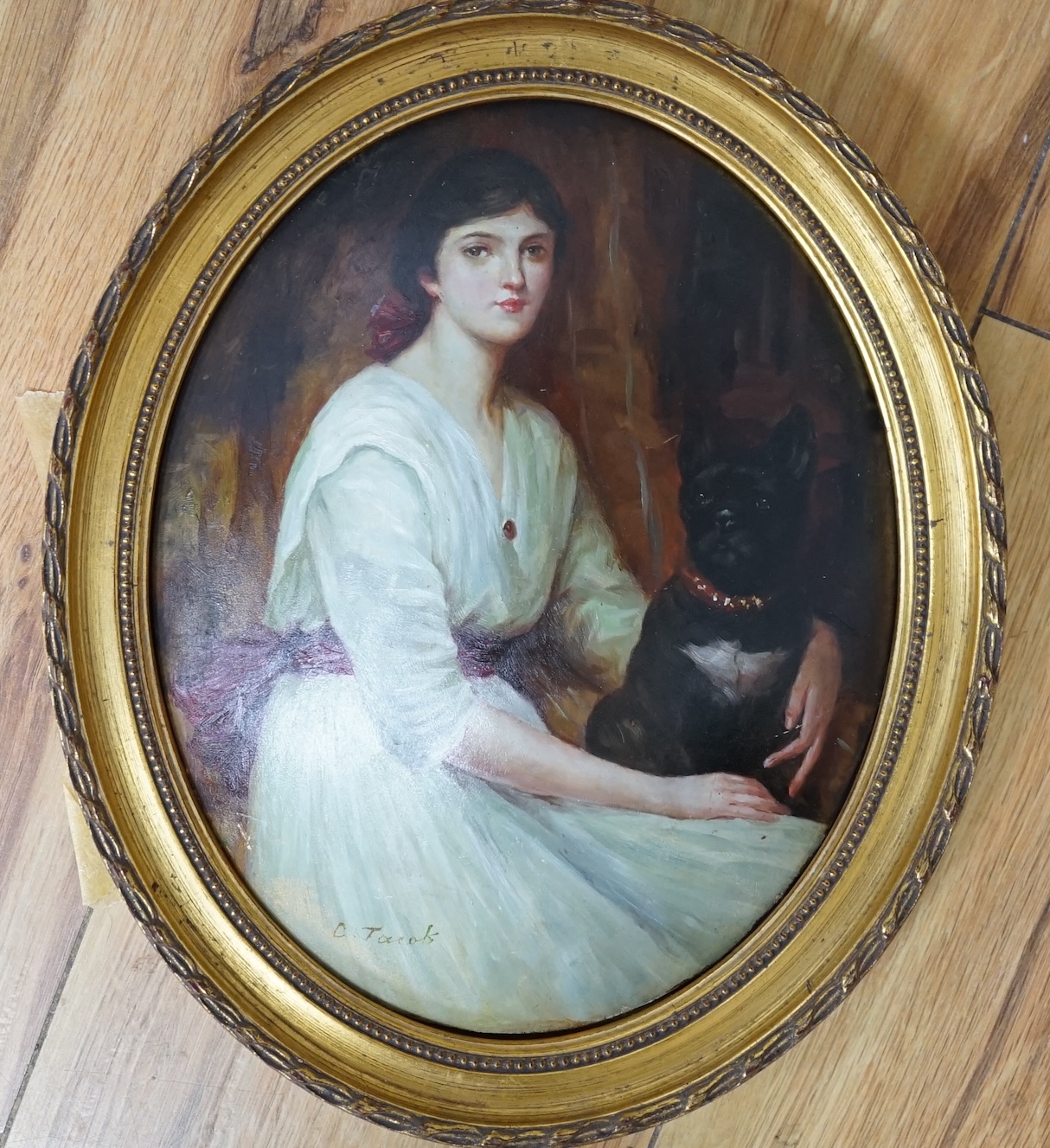 F. Jacob, oval oil on moulded composition, Study of a young lady with a dog, signed, 24 x 19cm, gilt frame. Condition - fair to good